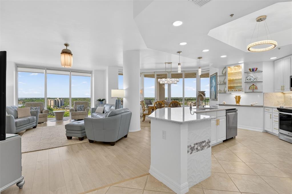 An open-concept living and kitchen area with light wood floors, white cabinetry, and floor-to-ceiling windows — 3426 HANCOCK BRIDGE PARKWAY UNIT 1008, NORTH FORT MYERS, FL
