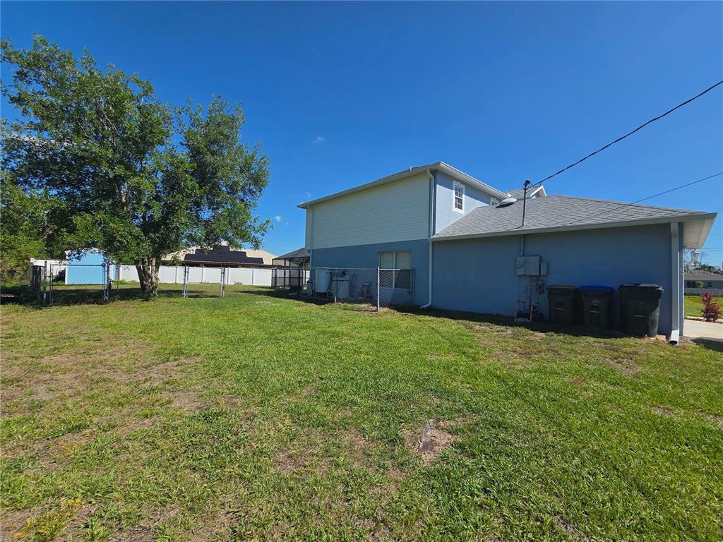 The exterior of a two-story blue house features a grassy yard and a chain-link fence — 1389 TIMBERHILL STREET, NORTH PORT, FL
