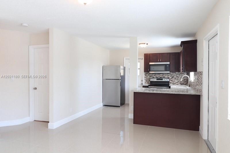 A kitchen features dark wood cabinets, stainless steel appliances, and a granite-topped breakfast bar — 1861 NW 59th Way, Sunrise FL 33313, SUNRISE, FL