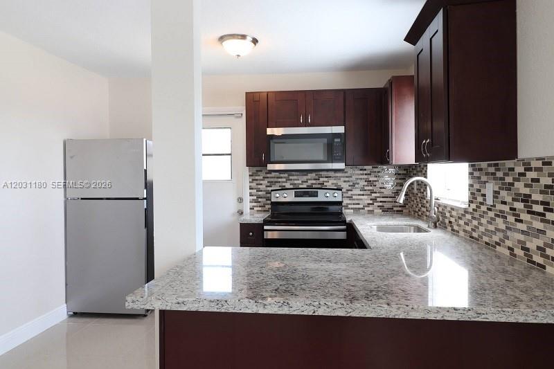 A kitchen features dark wood cabinets, granite countertops, stainless steel appliances, and a tiled backsplash — 1861 NW 59th Way, Sunrise FL 33313, SUNRISE, FL