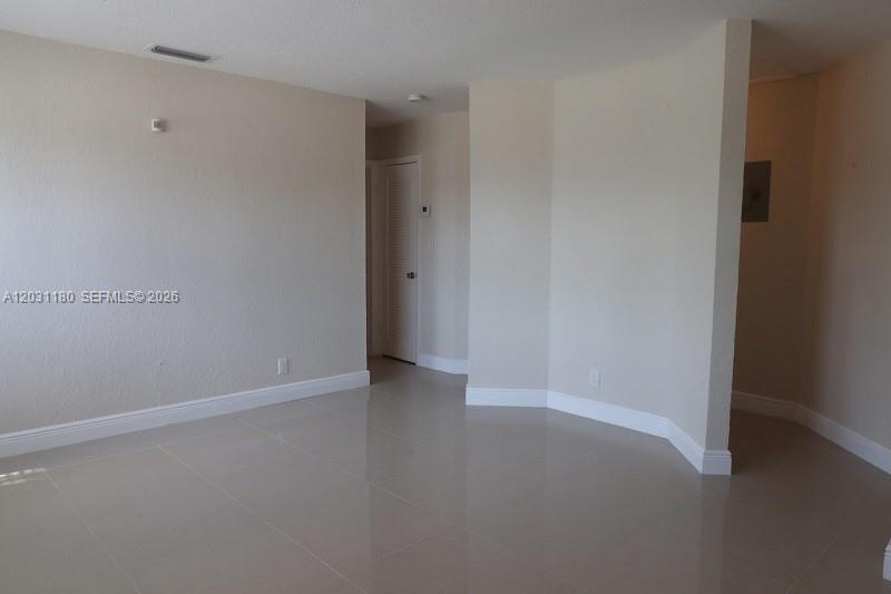 An empty room features beige walls, light-colored tile flooring, and a white interior door — 1861 NW 59th Way, Sunrise FL 33313, SUNRISE, FL