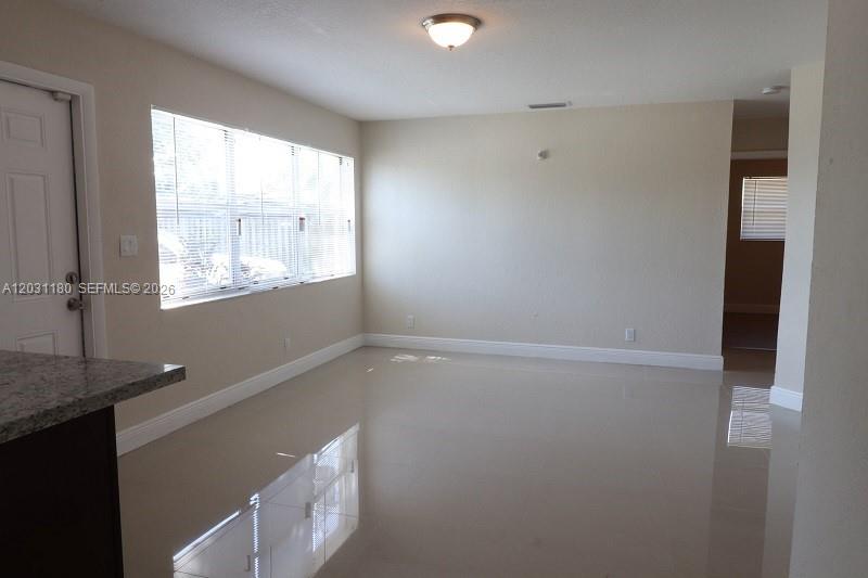 A bright, empty room features light-colored tile flooring, beige walls, and a large window — 1861 NW 59th Way, Sunrise FL 33313, SUNRISE, FL