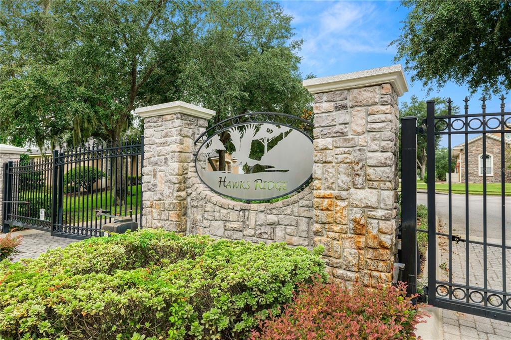 A stone entrance monument with a metal sign reading Hawks Ridge stands beside a gate — 3333 HAWKS RIDGE DRIVE, LAKELAND, FL