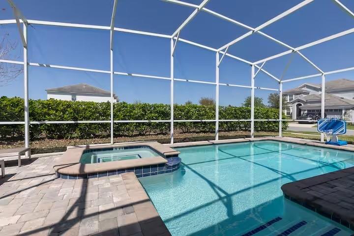 A screened-in swimming pool and spa with a paver deck and a basketball hoop — 9033 HAZARD STREET, DAVENPORT, FL