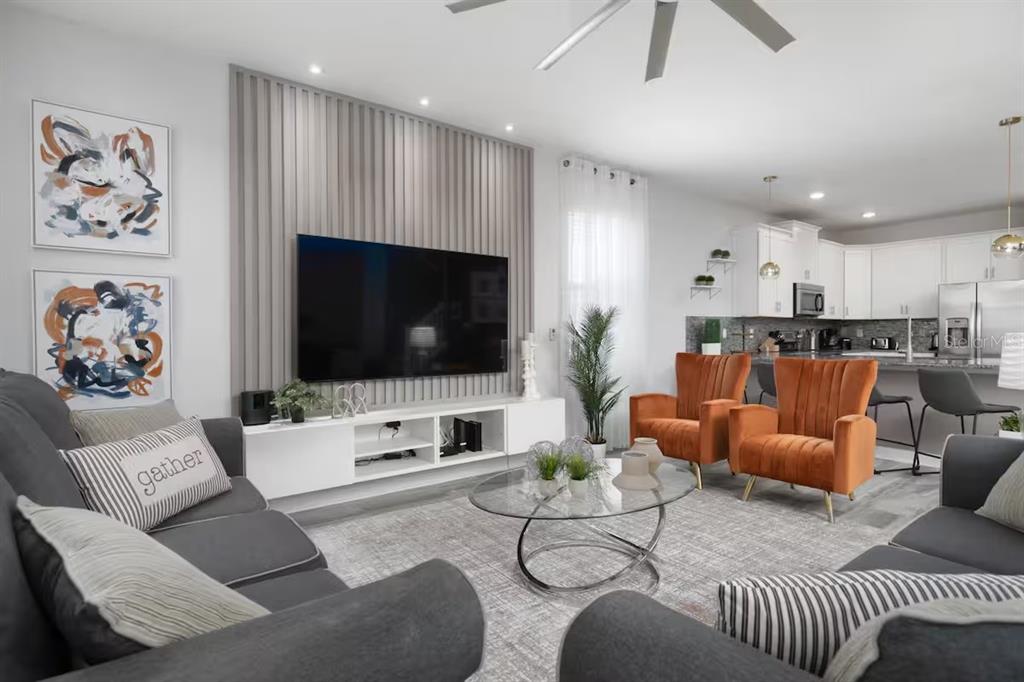 A living room with a slatted accent wall, grey sofas, and two orange velvet chairs — 9033 HAZARD STREET, DAVENPORT, FL