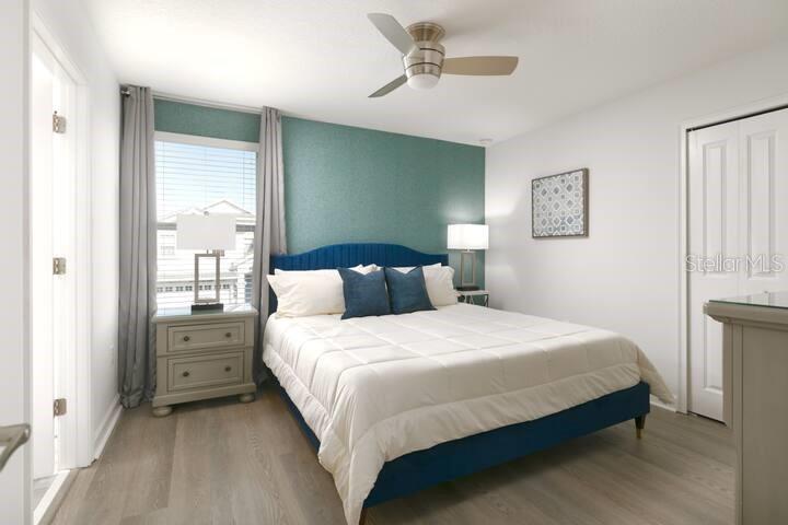 A bedroom features a blue upholstered bed, a teal accent wall, and light wood flooring — 9033 HAZARD STREET, DAVENPORT, FL