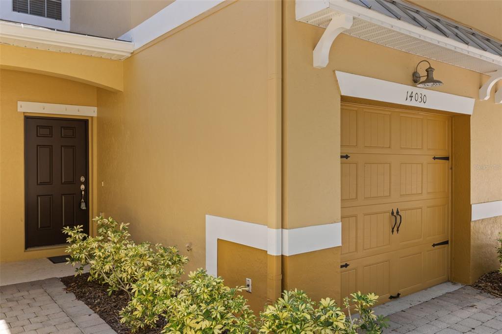 A yellow exterior wall features a dark brown front door and a garage door — 14030 SPARKLING COVE LANE UNIT 603, WINDERMERE, FL