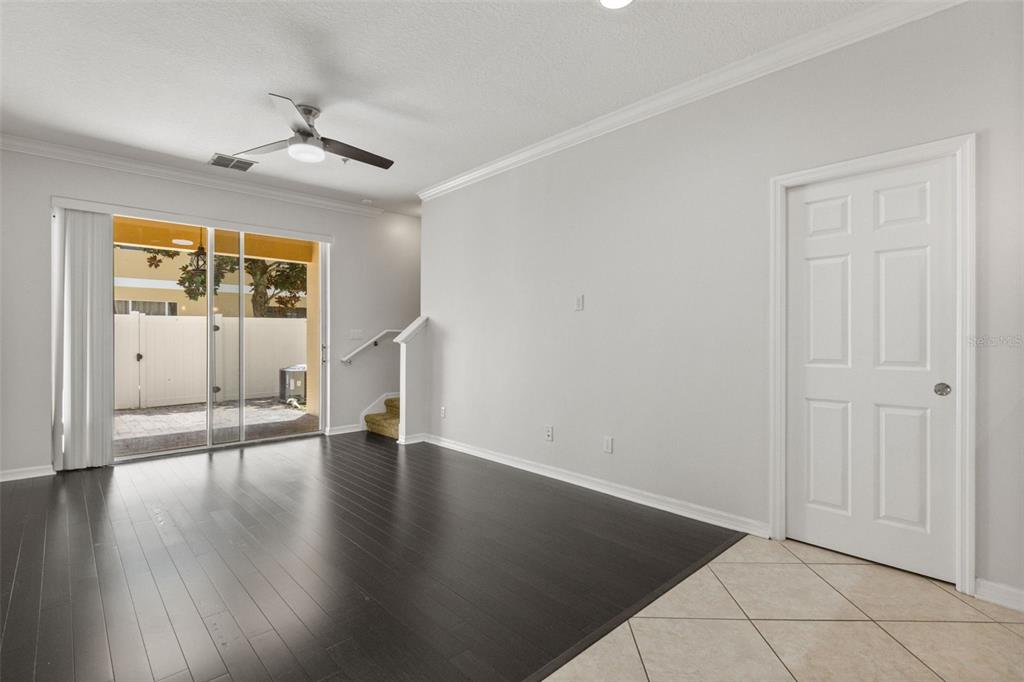 A room with dark wood flooring, a ceiling fan, a sliding glass door, and stairs — 14030 SPARKLING COVE LANE UNIT 603, WINDERMERE, FL