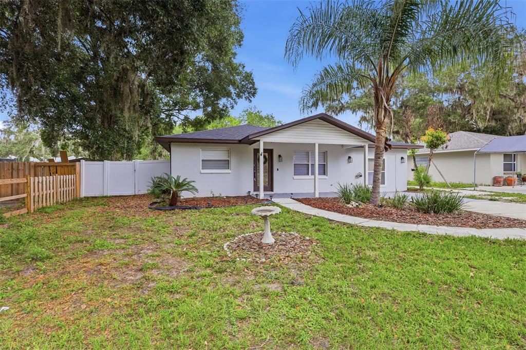 A single-story house with a white exterior, a front porch, and a palm tree — 2602 WESTSIDE DRIVE, LEESBURG, FL