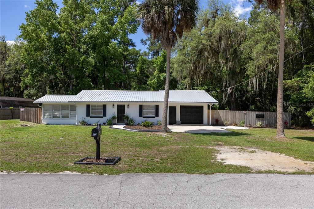 A single-story white house with a metal roof, a garage, and a large front yard — 113 BROWNS ROAD, SAN MATEO, FL