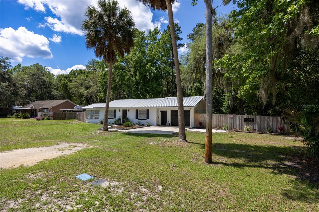 A white single-story house with a metal roof sits on a grassy lot with trees — 113 BROWNS ROAD, SAN MATEO, FL