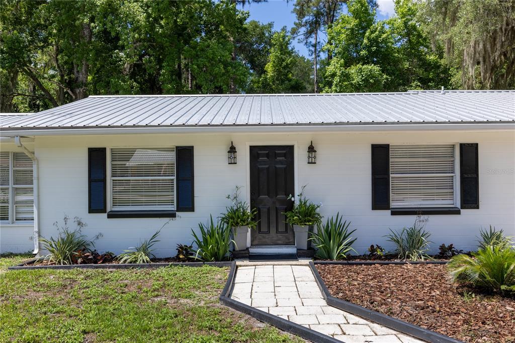 A white house with a metal roof, black shutters, and a stone walkway — 113 BROWNS ROAD, SAN MATEO, FL