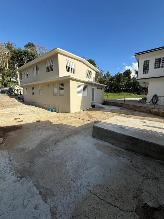 A two-story beige house with white shutters stands on a large concrete lot — Aibonito LA PLATA, AIBONITO, PR