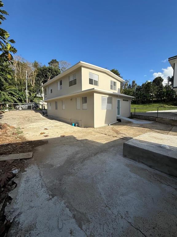 A two-story beige house with white window shutters sits on a large concrete lot — Aibonito LA PLATA, AIBONITO, PR