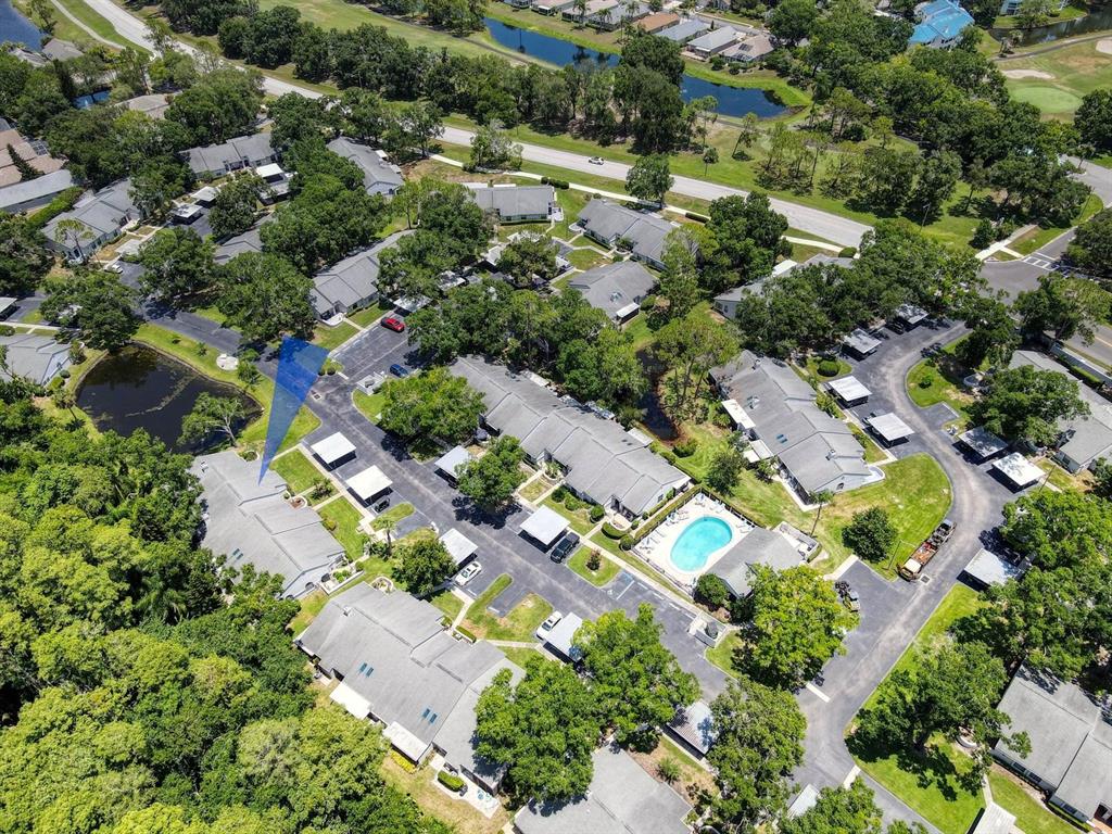 An aerial view shows a residential complex with multiple buildings, a swimming pool, and ponds — 3454 KILLDEER PLACE, PALM HARBOR, FL