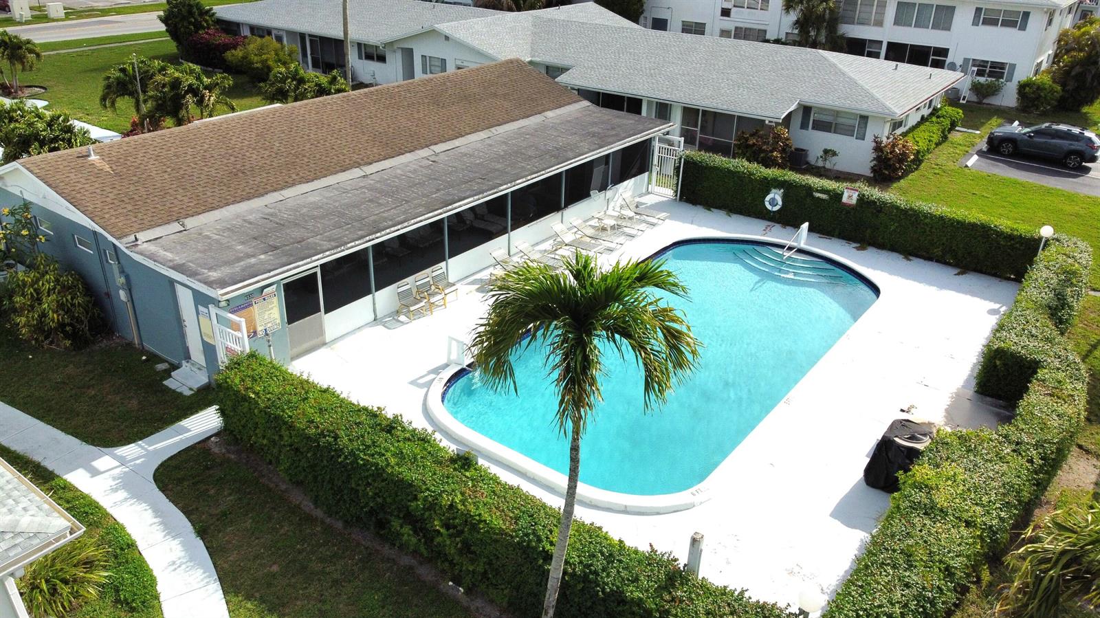 An aerial view of a rectangular swimming pool surrounded by a hedge and a building — 6560 Winfield Boulevard # 102, Margate FL 33063, MARGATE, FL