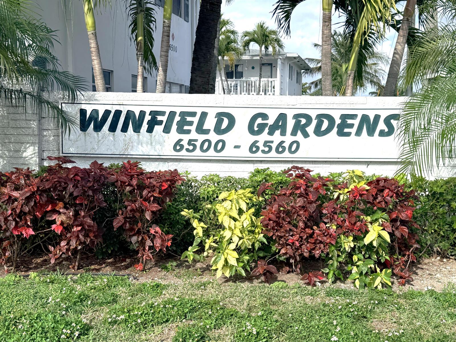 A sign for Winfield Gardens stands in front of a building with palm trees — 6560 Winfield Boulevard # 102, Margate FL 33063, MARGATE, FL