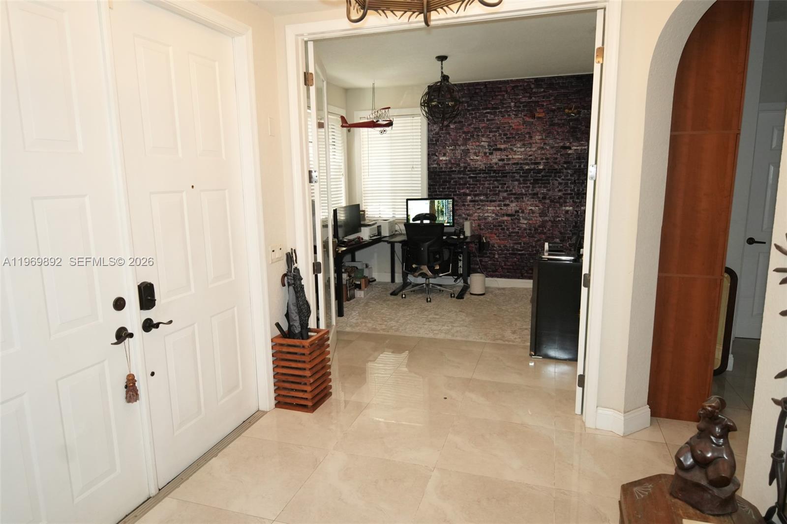 A tiled entryway leads into a home office featuring a dark brick accent wall — 2706 Kinsington Cir # 2, Weston FL 33332, WESTON, FL