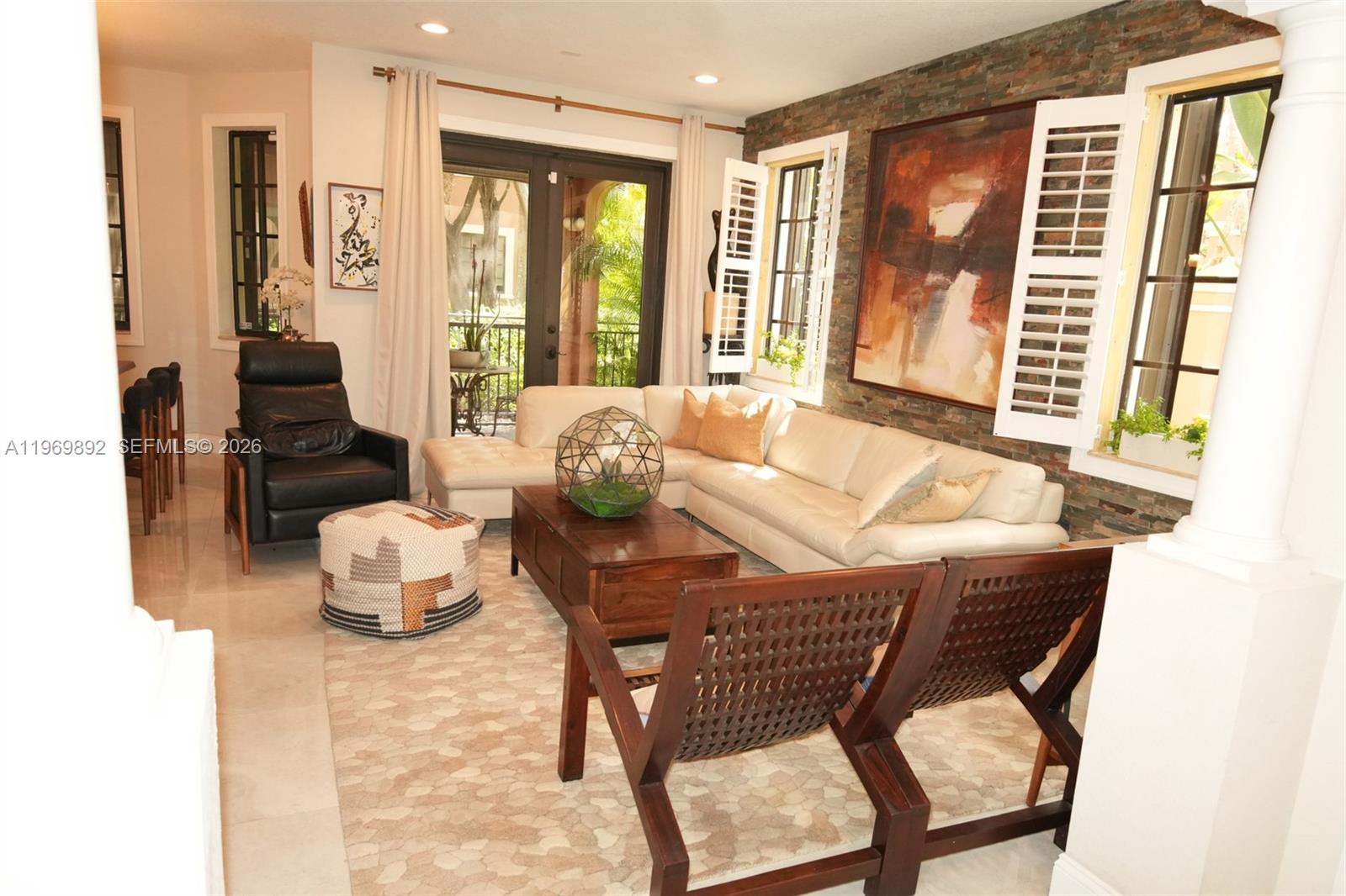 A living room features a white sectional sofa, stone accent wall, and two wooden chairs — 2706 Kinsington Cir # 2, Weston FL 33332, WESTON, FL