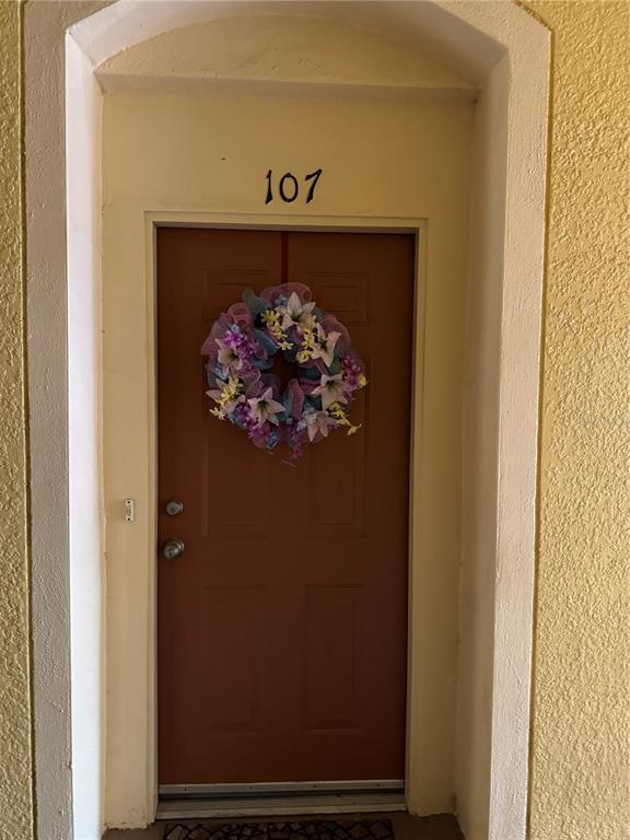 A brown front door with a floral wreath and the number 107 above it — 6335 CONTESSA DRIVE UNIT 107, ORLANDO, FL