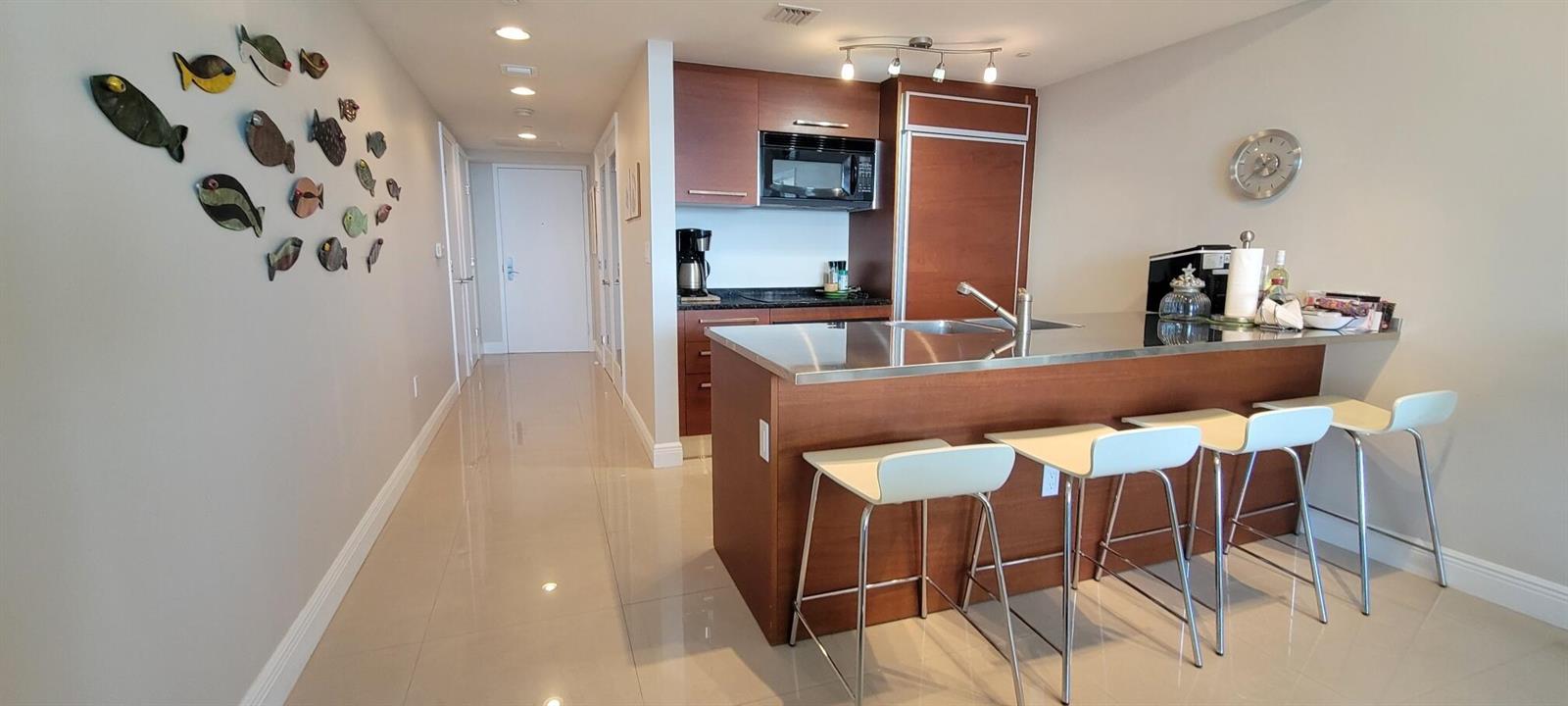 A kitchen with a stainless steel island, bar stools, and decorative fish on the wall — 1850 S Ocean Drive # 3806, Hallandale Beach FL 33009, HALLANDALE BEACH, FL