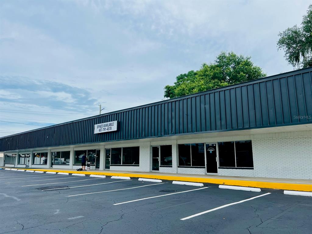 A single-story commercial strip mall building with a dark metal roof and white brick exterior — 1780 E DUVAL STREET Unit 120, LAKE CITY, FL