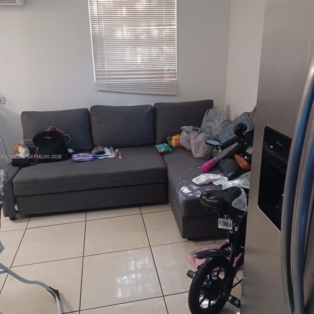 A gray sectional sofa sits in a room with white walls and tiled flooring — 5250 NW 24th Ave, Miami FL 33142, MIAMI, FL