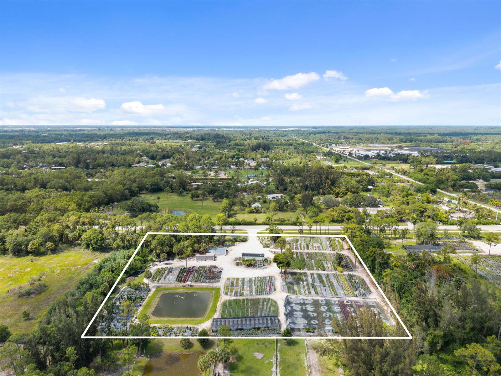 An aerial view shows a plant nursery with a pond and greenhouses within a property — 14650 Okeechobee Boulevard, FL 33470, FL