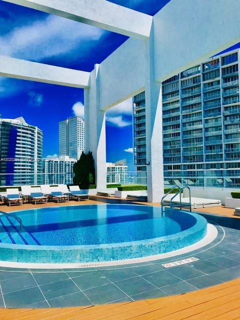A circular swimming pool sits on a rooftop terrace surrounded by modern high-rise buildings — 500 Brickell Ave # 2208, Miami FL 33131, MIAMI, FL