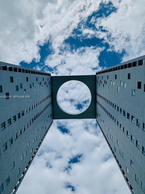 A low-angle view of two tall, gray apartment buildings connected by a bridge with a circular cutout — 500 Brickell Ave # 2208, Miami FL 33131, MIAMI, FL