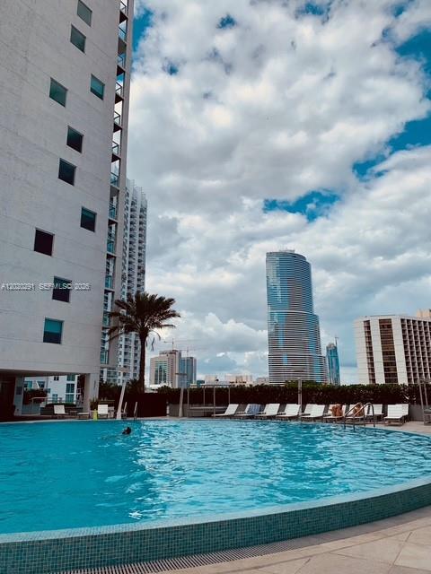 A swimming pool sits in front of a tall apartment building with city skyscrapers nearby — 500 Brickell Ave # 2208, Miami FL 33131, MIAMI, FL