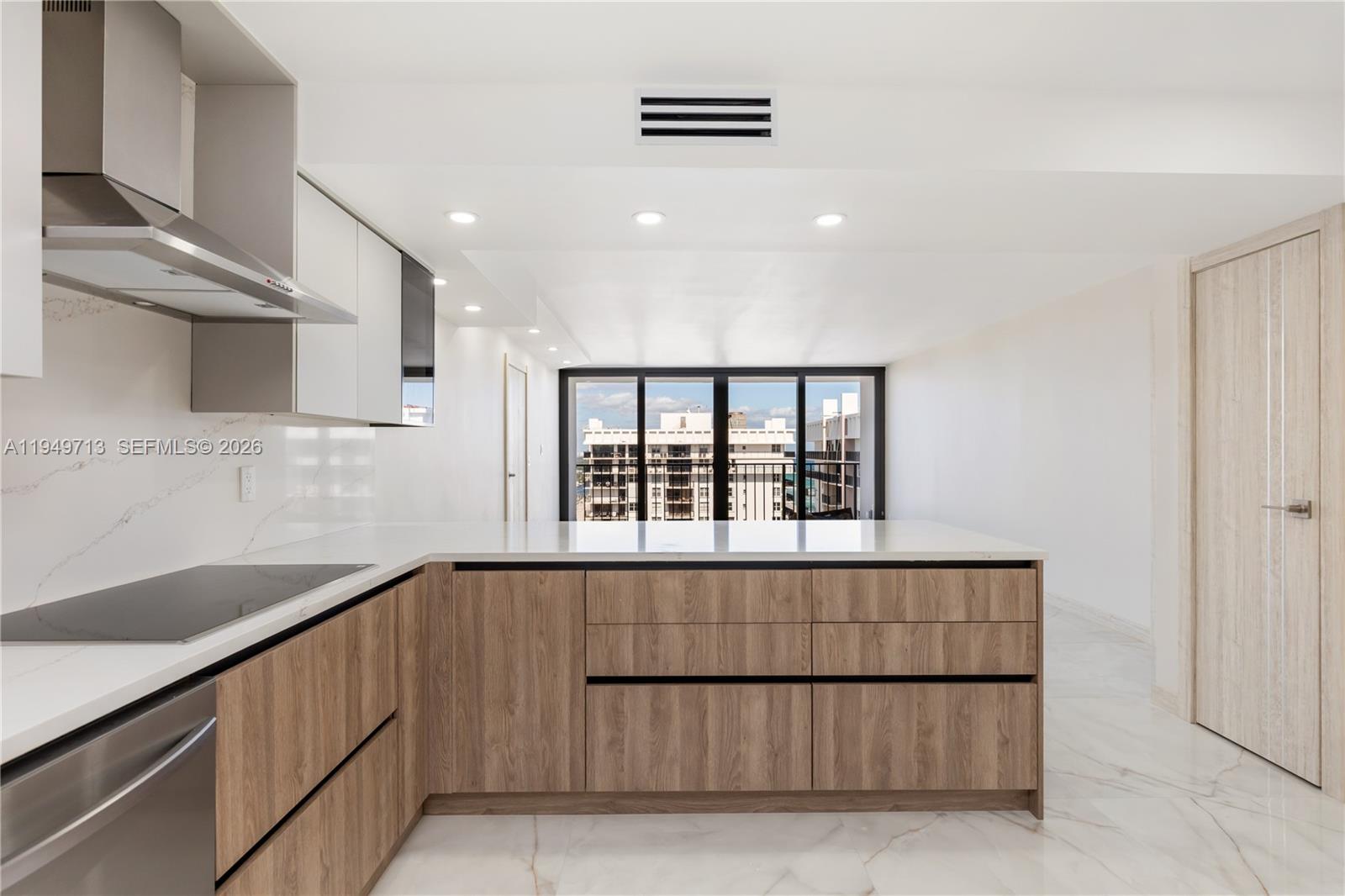 A modern kitchen features wood-grain cabinets, white countertops, and a view of buildings outside — 2401 S Ocean Dr # A4, Hollywood FL 33019, HOLLYWOOD, FL