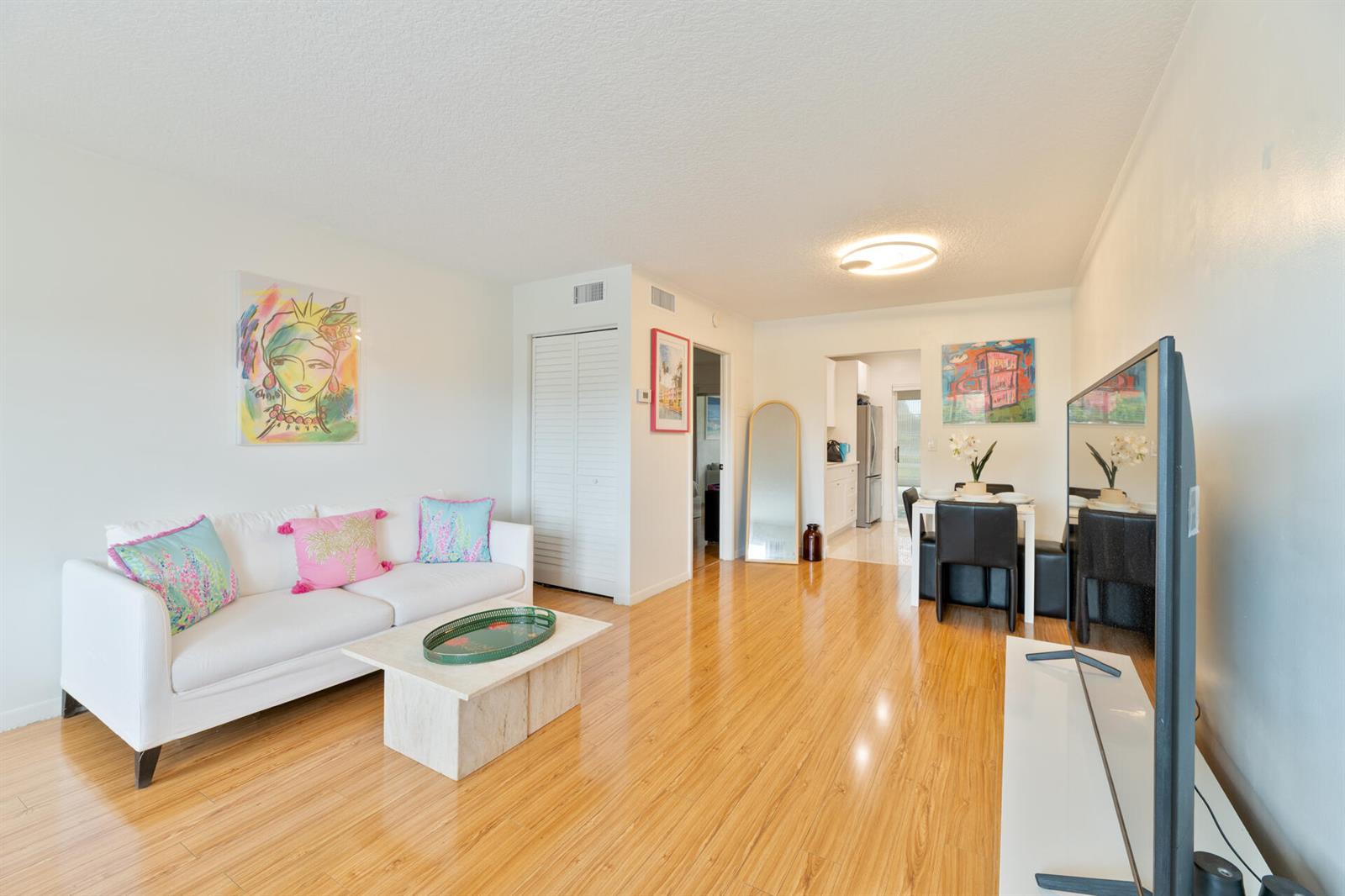 A living room with light wood floors, a white sofa, and an adjacent dining area — 32 Abbey Lane # 205, Delray Beach FL 33446, DELRAY BEACH, FL