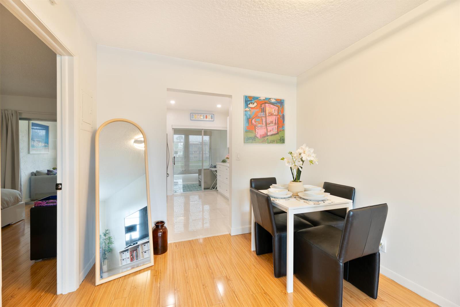 A dining area with a white table, four black chairs, and a floor-length arched mirror — 32 Abbey Lane # 205, Delray Beach FL 33446, DELRAY BEACH, FL