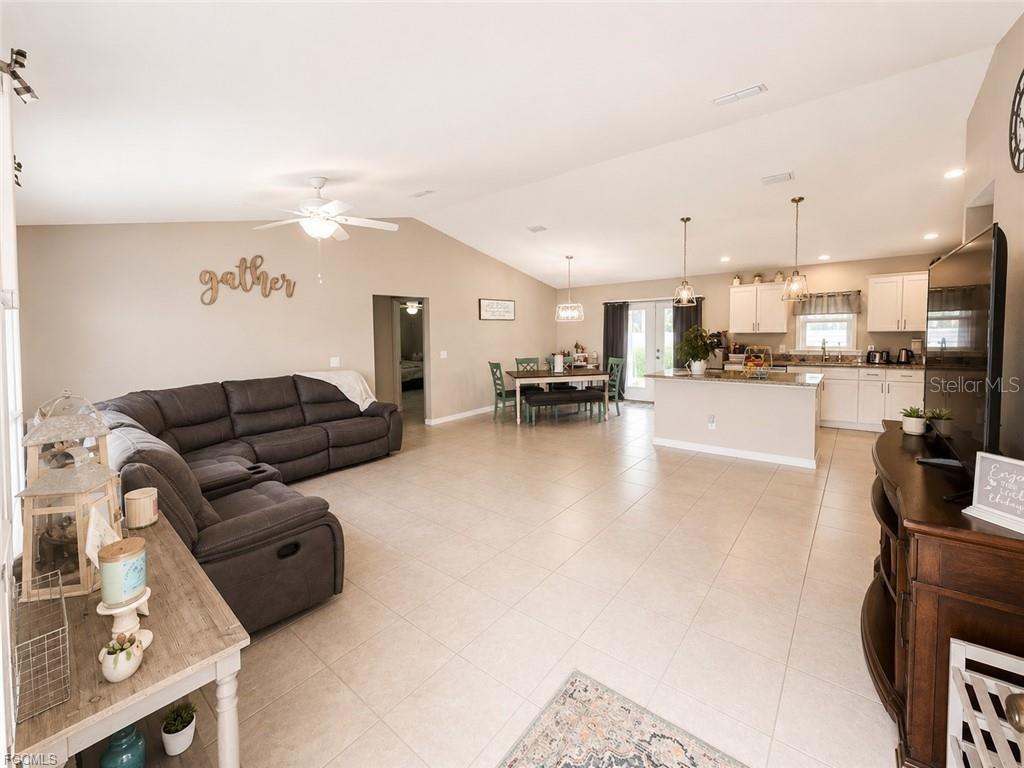 An open-concept living room and kitchen featuring tile flooring, a sectional sofa, and dining area — 5405 BEARUP STREET, PORT CHARLOTTE, FL