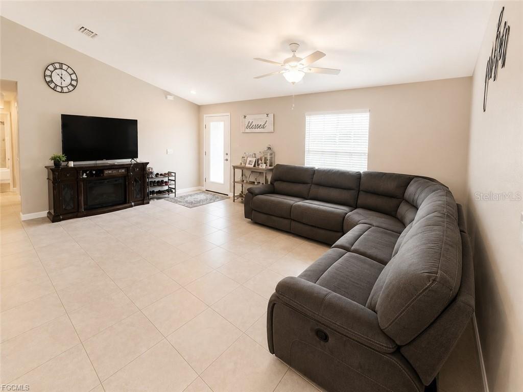 A living room features a large sectional sofa, a television on a console, and tile flooring — 5405 BEARUP STREET, PORT CHARLOTTE, FL