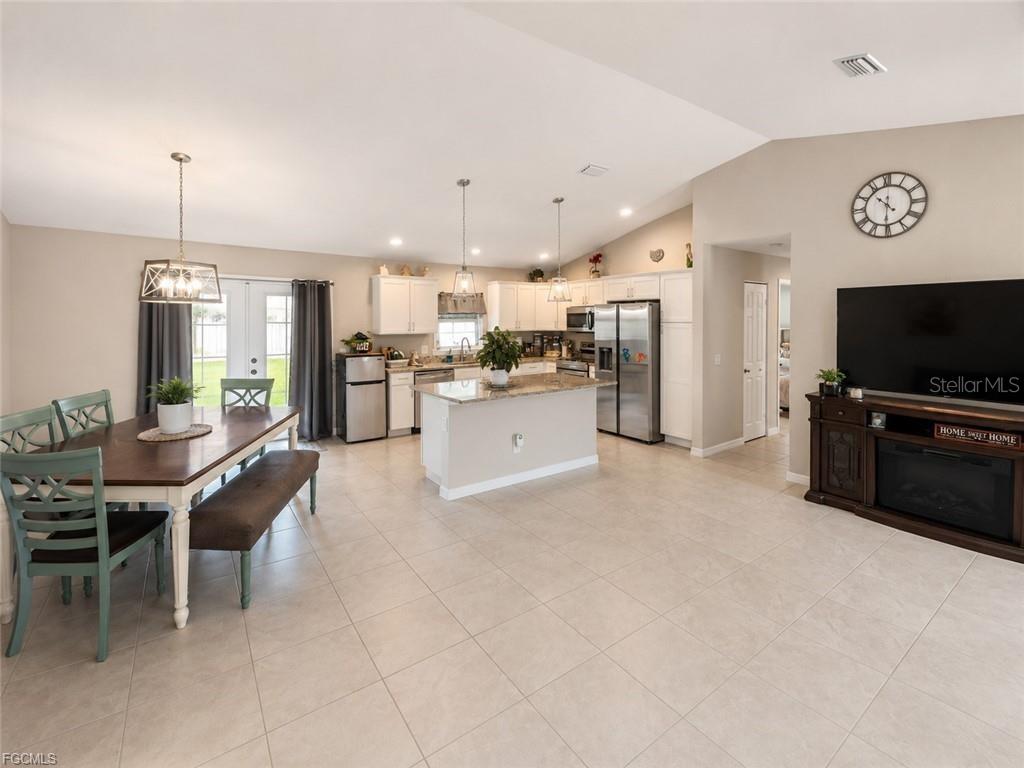 An open-concept kitchen and dining area features tile flooring, white cabinetry, and a center island — 5405 BEARUP STREET, PORT CHARLOTTE, FL