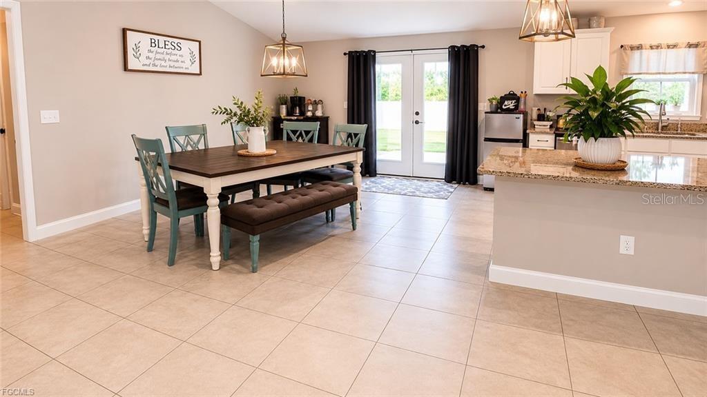 A dining area with a wooden table and bench sits adjacent to a kitchen island — 5405 BEARUP STREET, PORT CHARLOTTE, FL