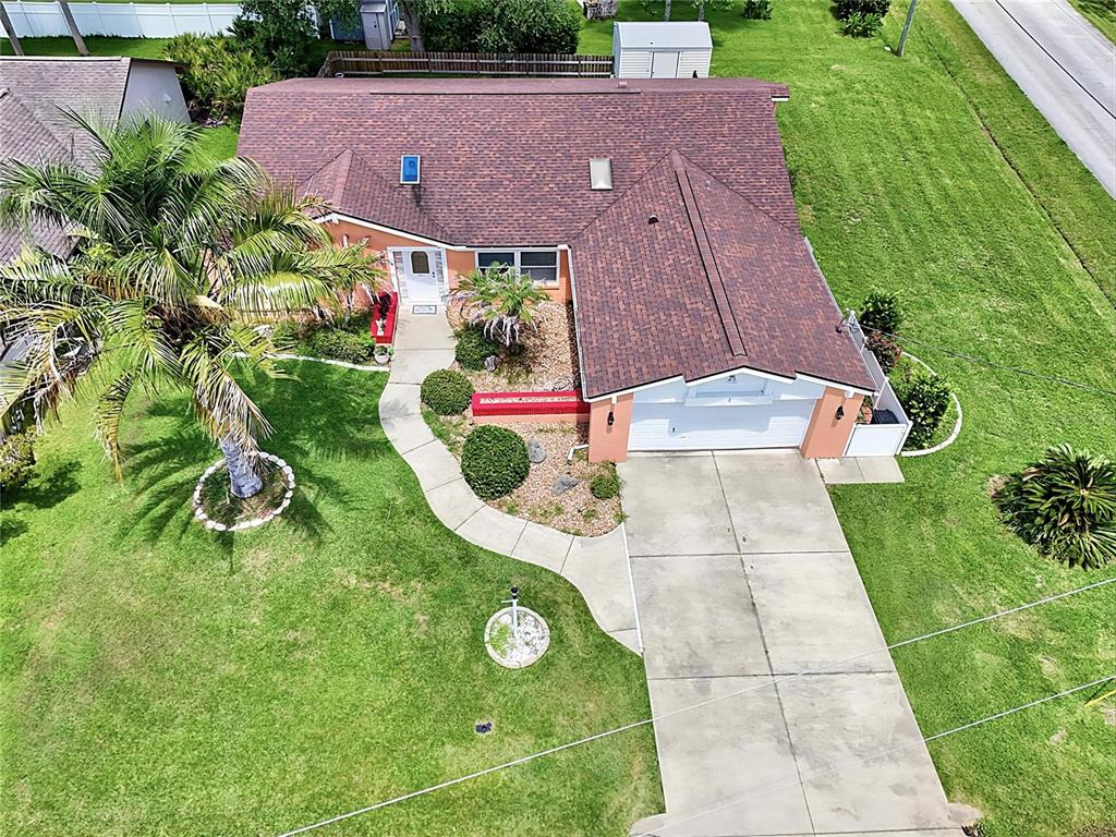 An aerial view shows a single-story house with a brown roof, garage, and palm tree — 2 WINDERMERE PLACE, PALM COAST, FL