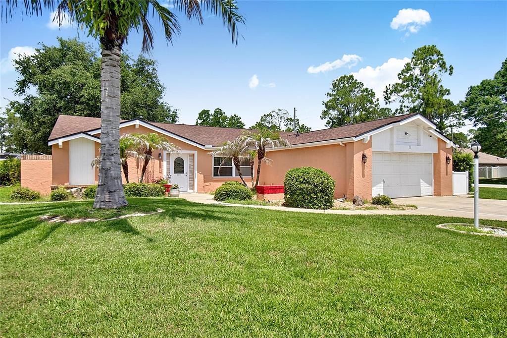 A single-story peach-colored house with a white garage door and a large front lawn — 2 WINDERMERE PLACE, PALM COAST, FL