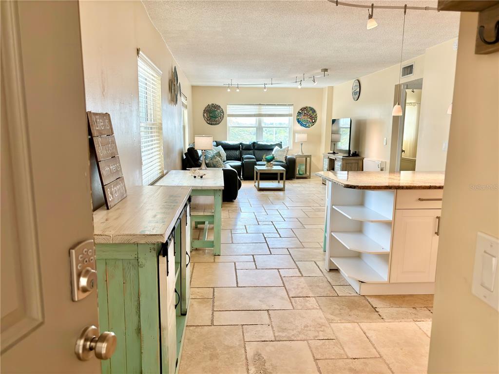 An open-concept living area features tile flooring, a kitchen island, and a sectional sofa — 18650 GULF BOULEVARD UNIT 315, INDIAN SHORES, FL