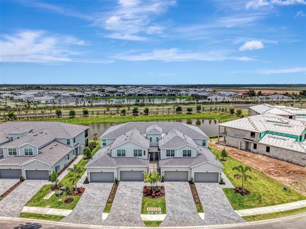 An aerial view shows a multi-unit residential building with gray roofs and paved driveways — 19227 CHERRYSTONE WAY UNIT #104, LAKEWOOD RANCH, FL