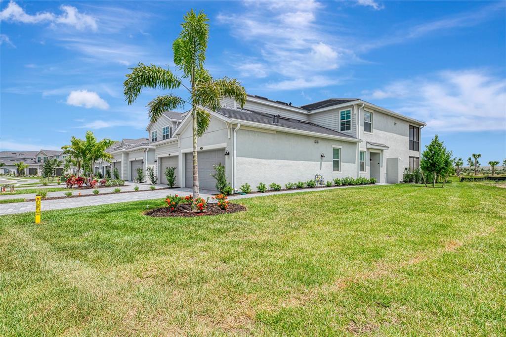 A two-story townhouse with a gray exterior, a paved driveway, and a palm tree — 19227 CHERRYSTONE WAY UNIT #104, LAKEWOOD RANCH, FL