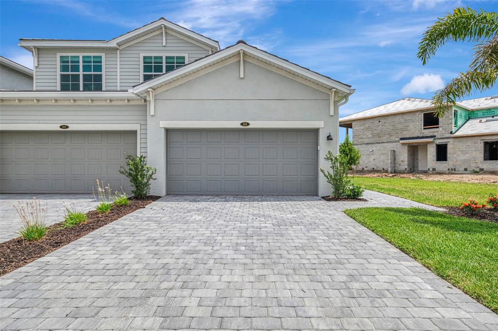 A gray two-story duplex with a paved driveway and a garage under a blue sky — 19227 CHERRYSTONE WAY UNIT #104, LAKEWOOD RANCH, FL