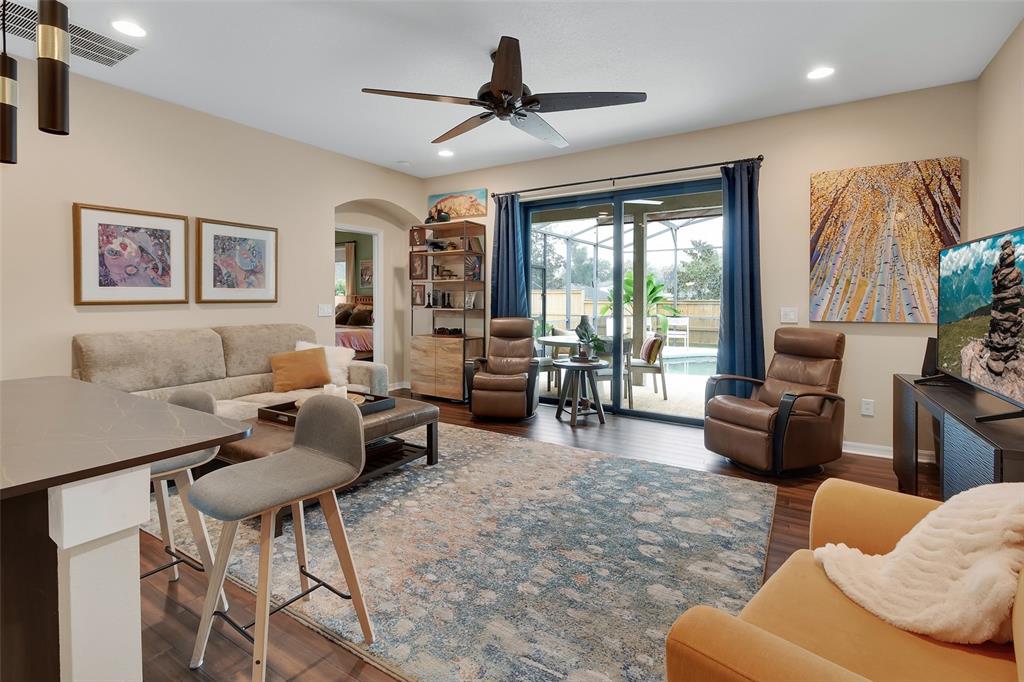 A living room features a sofa, two recliners, a patterned rug, and a sliding glass door — 404 COUNTRY VIEW CIRCLE, DELAND, FL