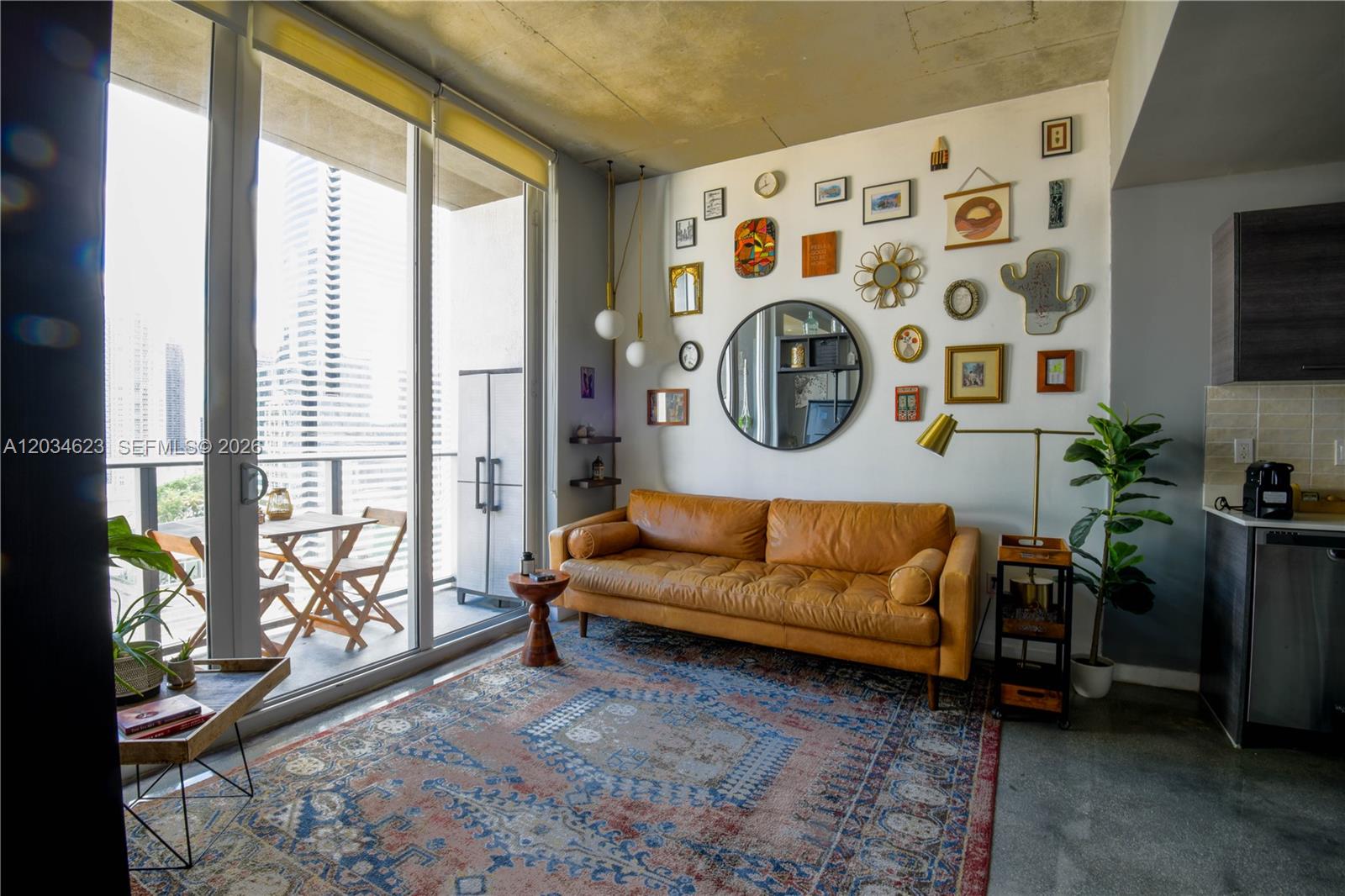 A living room features a leather sofa, gallery wall, area rug, and balcony access — 151 SE 1st St # 1907, Miami FL 33131, MIAMI, FL
