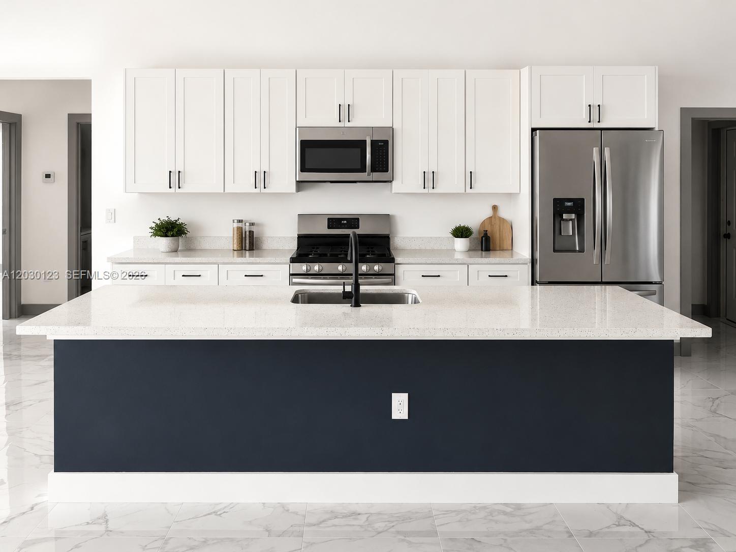 A modern kitchen features a dark blue island, white cabinets, stainless steel appliances, and quartz countertops — 3000 Nelson Rd N, Cape Coral FL 33993, CAPE CORAL, FL