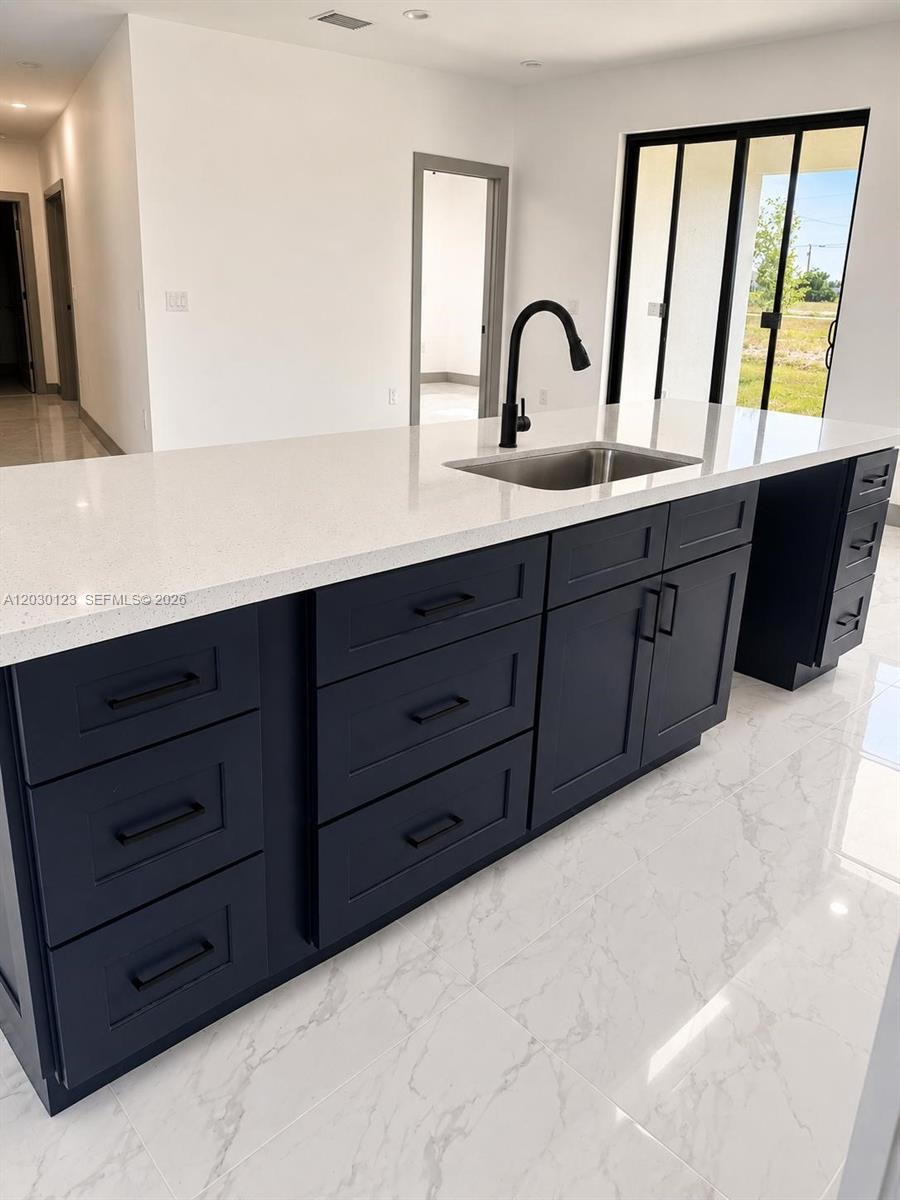 A kitchen island with dark blue cabinets, a white countertop, and a stainless steel sink — 3000 Nelson Rd N, Cape Coral FL 33993, CAPE CORAL, FL
