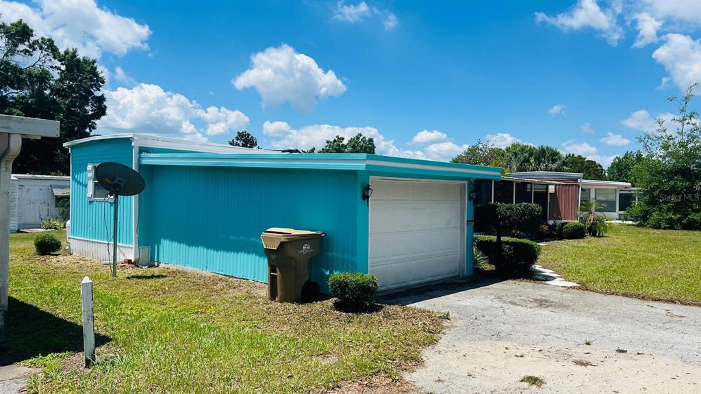 A bright blue mobile home features an attached garage and a satellite dish on the side — 14750 OLD US HIGHWAY 441, TAVARES, FL