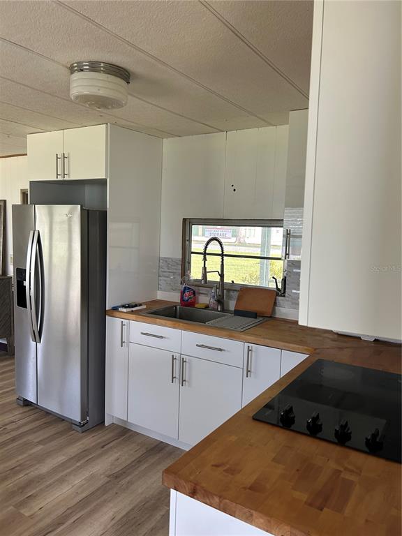 A kitchen features white cabinets, a stainless steel refrigerator, and wood-block countertops — 14750 OLD US HIGHWAY 441, TAVARES, FL